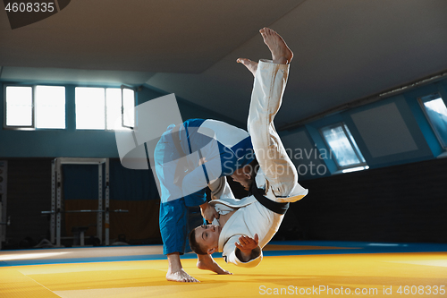 Image of Two young judo fighters in kimono training martial arts in the gym with expression, in action and motion