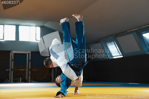 Image of Two young judo fighters in kimono training martial arts in the gym with expression, in action and motion