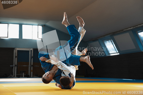 Image of Two young judo fighters in kimono training martial arts in the gym with expression, in action and motion