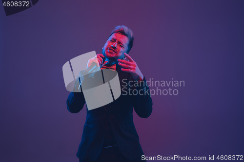Image of Young caucasian musician, performer singing, dancing in neon light on gradient background