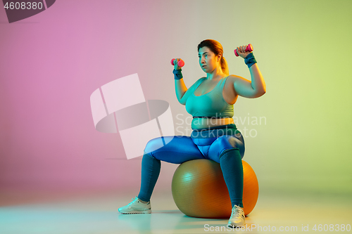 Image of Young caucasian plus size female model\'s training on gradient purple green background