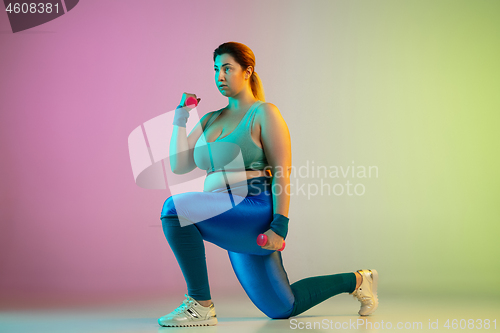 Image of Young caucasian plus size female model\'s training on gradient purple green background