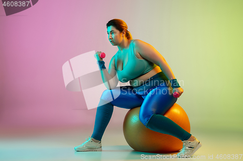 Image of Young caucasian plus size female model\'s training on gradient purple green background