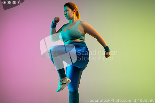 Image of Young caucasian plus size female model\'s training on gradient purple green background