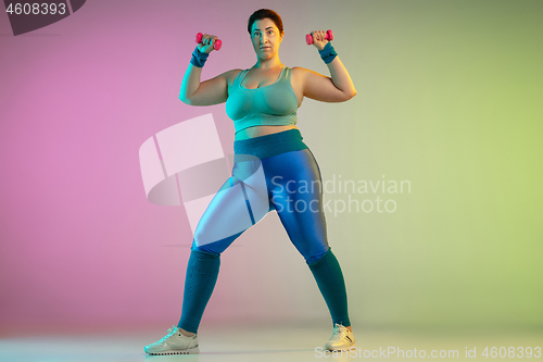 Image of Young caucasian plus size female model\'s training on gradient purple green background