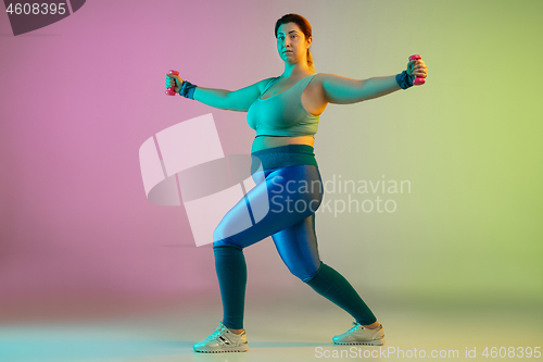 Image of Young caucasian plus size female model\'s training on gradient purple green background