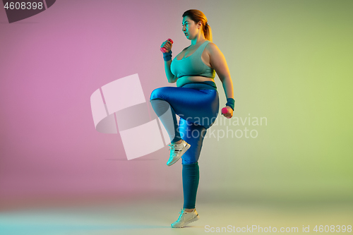 Image of Young caucasian plus size female model\'s training on gradient purple green background