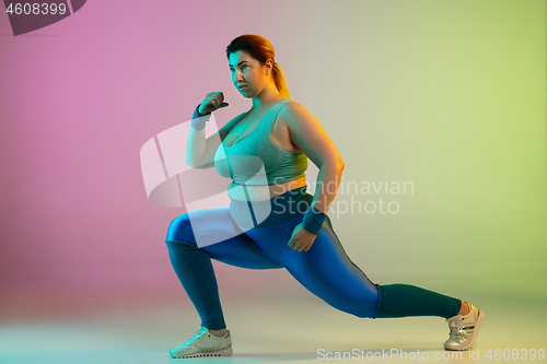 Image of Young caucasian plus size female model\'s training on gradient purple green background