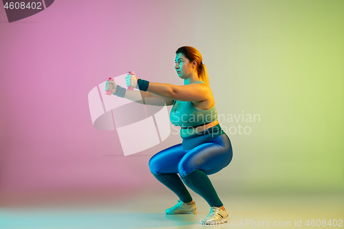 Image of Young caucasian plus size female model\'s training on gradient purple green background
