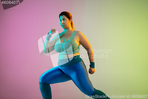 Image of Young caucasian plus size female model\'s training on gradient purple green background