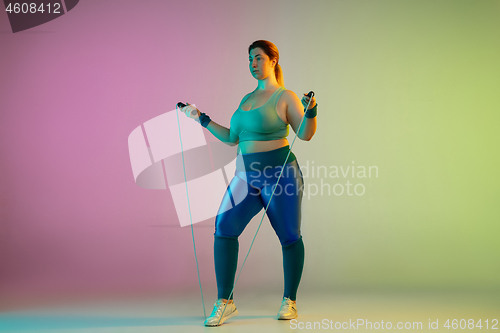 Image of Young caucasian plus size female model\'s training on gradient purple green background