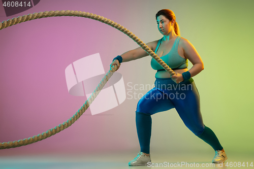 Image of Young caucasian plus size female model\'s training on gradient purple green background