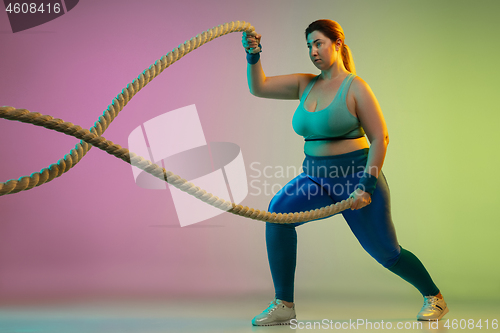 Image of Young caucasian plus size female model\'s training on gradient purple green background