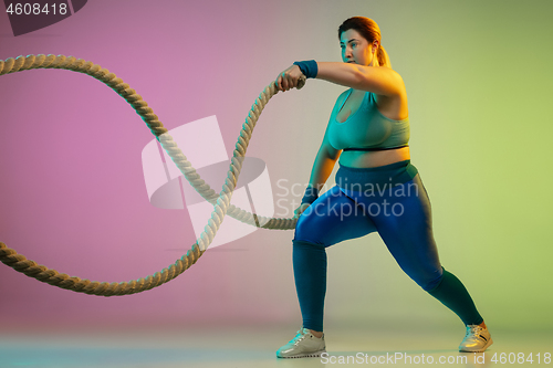 Image of Young caucasian plus size female model\'s training on gradient purple green background