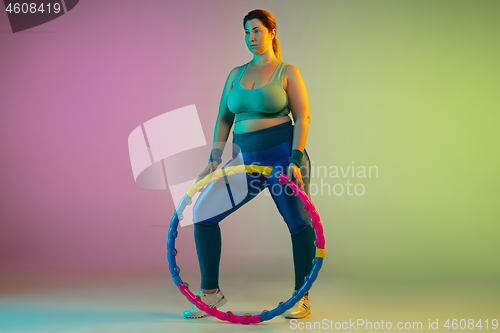 Image of Young caucasian plus size female model\'s training on gradient purple green background