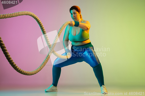 Image of Young caucasian plus size female model\'s training on gradient purple green background