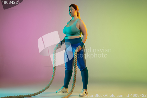 Image of Young caucasian plus size female model\'s training on gradient purple green background