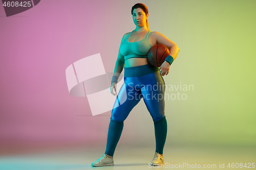 Image of Young caucasian plus size female model\'s training on gradient purple green background