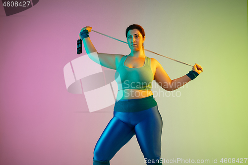 Image of Young caucasian plus size female model\'s training on gradient purple green background