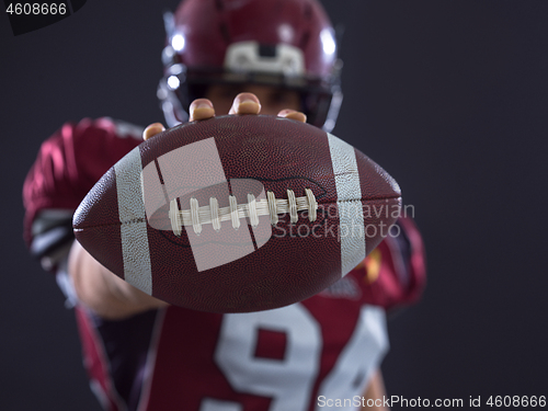 Image of american football player showing football to camera