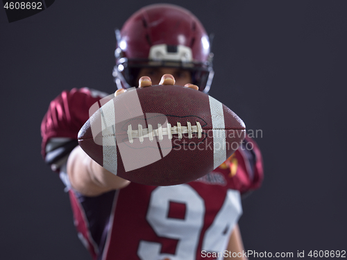 Image of american football player showing football to camera