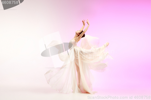 Image of Ballerina. Young graceful female ballet dancer dancing over pink studio. Beauty of classic ballet.