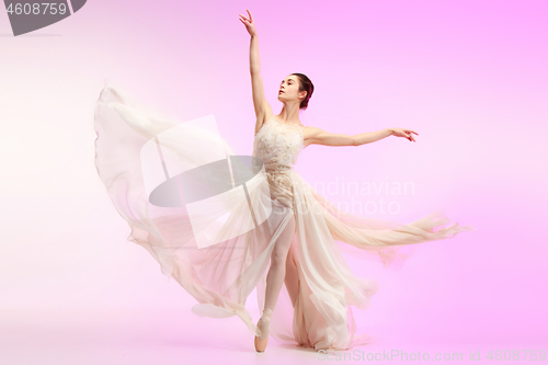 Image of Ballerina. Young graceful female ballet dancer dancing over pink studio. Beauty of classic ballet.