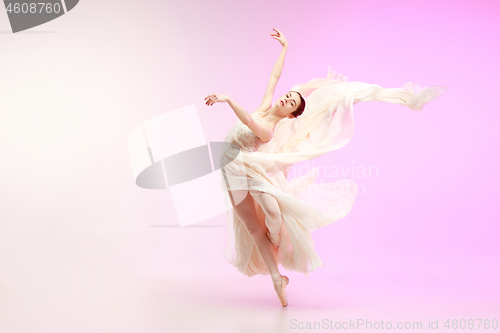 Image of Ballerina. Young graceful female ballet dancer dancing over pink studio. Beauty of classic ballet.