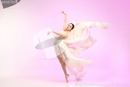 Image of Ballerina. Young graceful female ballet dancer dancing over pink studio. Beauty of classic ballet.