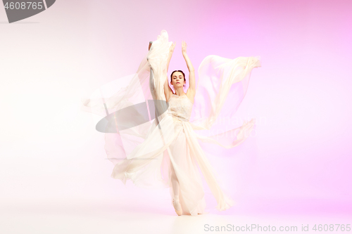 Image of Ballerina. Young graceful female ballet dancer dancing over pink studio. Beauty of classic ballet.