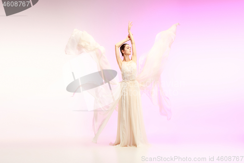 Image of Ballerina. Young graceful female ballet dancer dancing over pink studio. Beauty of classic ballet.