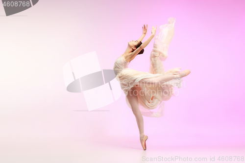 Image of Ballerina. Young graceful female ballet dancer dancing over pink studio. Beauty of classic ballet.