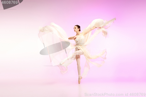 Image of Ballerina. Young graceful female ballet dancer dancing over pink studio. Beauty of classic ballet.