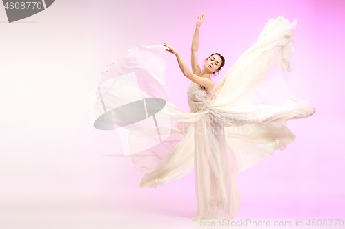 Image of Ballerina. Young graceful female ballet dancer dancing over pink studio. Beauty of classic ballet.