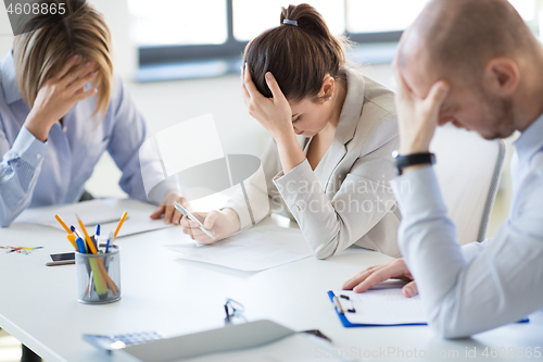 Image of stressed business team with papers at office