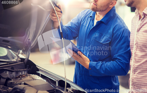 Image of auto mechanic with clipboard and man at car shop