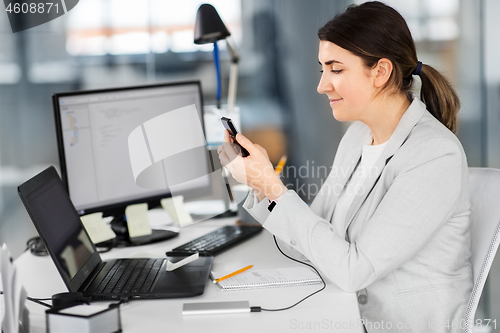 Image of businesswoman charging smartphone by power bank