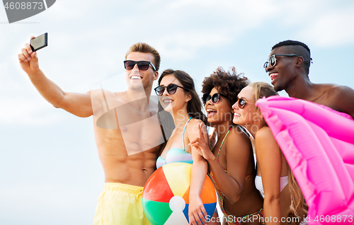 Image of happy friends taking selfie on summer beach