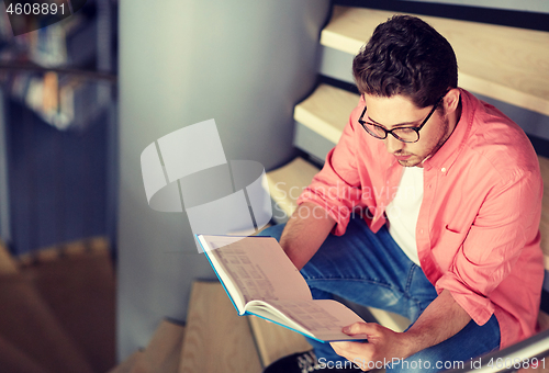 Image of student boy or young man reading book at library