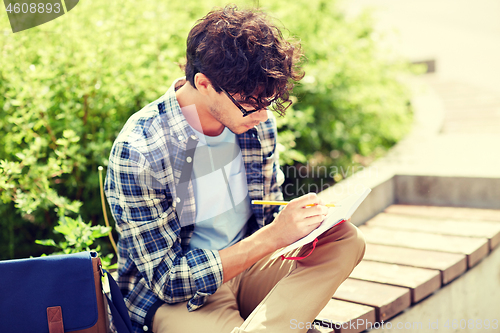 Image of man with notebook or diary writing on city street