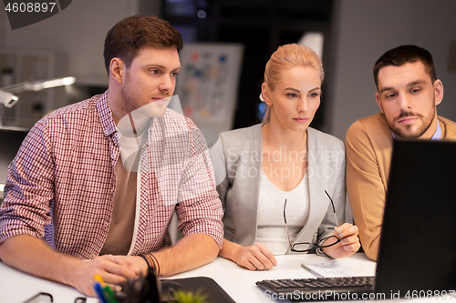 Image of business team with computer working late at office