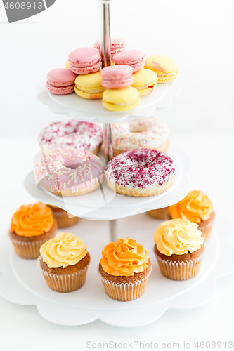 Image of glazed donuts, cupcakes and macarons on stand