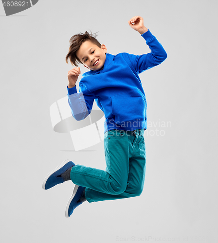 Image of portrait of smiling boy in blue hoodie jumping