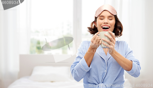 Image of woman in pajama and sleeping mask drinking coffee