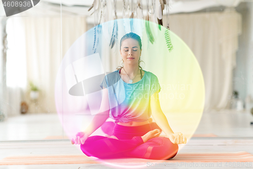 Image of woman meditating in lotus pose at yoga studio