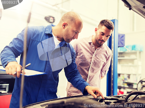 Image of auto mechanic with clipboard and man at car shop