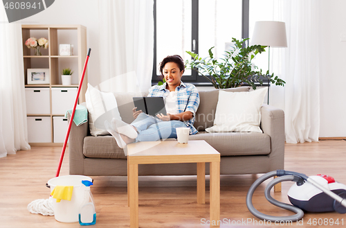 Image of woman with tablet pc resting after home cleaning