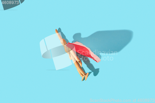 Image of Movable human miniature model in red cape as a superman flies up.