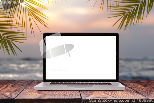 Image of Laptop mockup screen on wooden table against sea background.