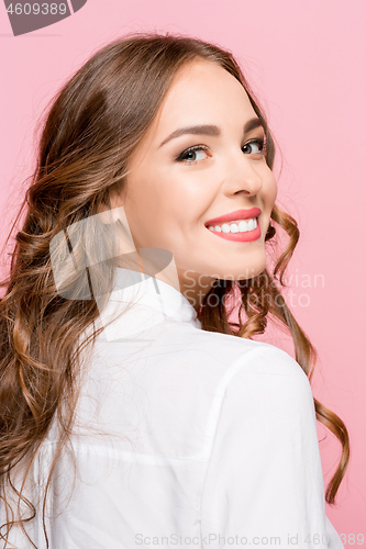 Image of The happy business woman standing and smiling against pink background.